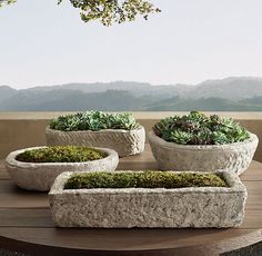 three cement planters sitting on top of a wooden table