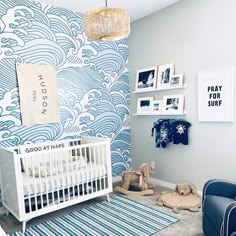 a baby's room decorated in blue and white with an ocean themed wallpaper