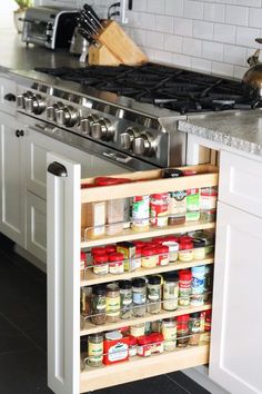 an open cabinet in the middle of a kitchen with lots of spices and condiments