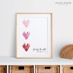 three baby footprints in pink and red on a white wall next to wicker baskets