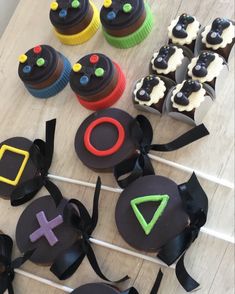 cupcakes with black icing and colorful decorations are on a table next to candy