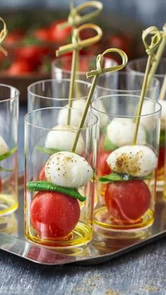 small glass cups filled with mozzarella and cherry tomatoes, topped with green leafy garnish