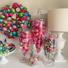 a table topped with lots of candy and glass vases next to a christmas wreath