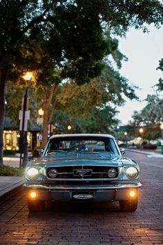 an old car is parked on the side of the road at night with its lights on