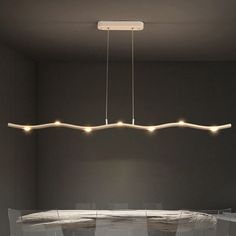 a dining room table and chairs with lights hanging from the ceiling above it in an empty room