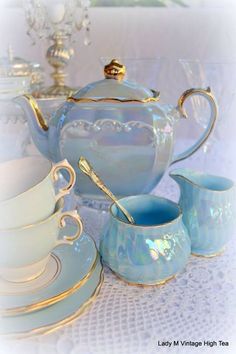 a blue tea set sitting on top of a table next to cups and saucers