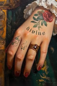 a close up of a person's hand with tattoos on their fingers and the word divine written on her ring