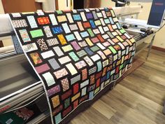 a quilt is being sewned on to a machine in a room with hard wood flooring