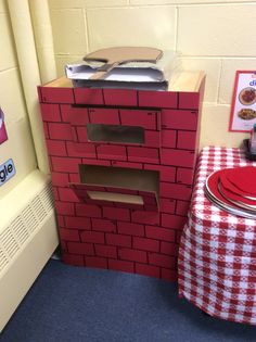 a red brick oven sitting next to a table with a checkered cloth on it