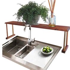 a stainless steel sink with a wooden shelf above it and a bowl of fruit on the counter