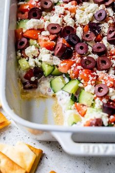 a casserole dish with olives, cucumber and feta cheese