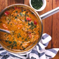 an overhead view of a stew in a pot with spoons and bowls on the side