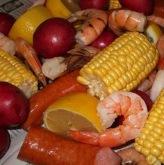 corn on the cob, potatoes, shrimp, and other foods are piled together