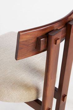 a close up of a wooden chair with a beige seat pad and backrests