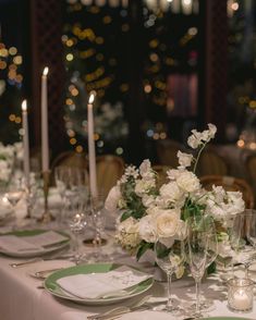 the table is set with white and green plates, silverware, and centerpieces