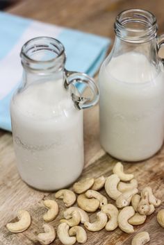 two jars filled with cashews sitting on top of a wooden table