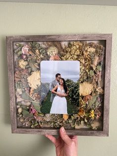 a person holding up a photo frame with flowers on it