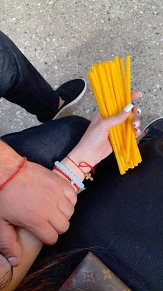 two people holding yellow sticks with their hands on each other's wrist, while sitting next to one another