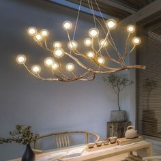 a chandelier made out of branches with lights hanging from the ceiling above it