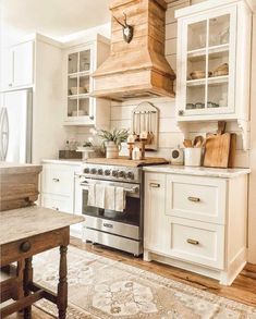 a kitchen with white cabinets and an oven in the center is filled with utensils