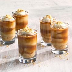 four glasses filled with desserts sitting on top of a table