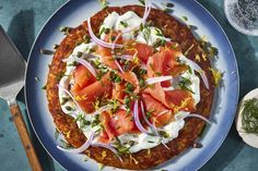 a blue plate topped with a pizza covered in toppings next to a knife and fork