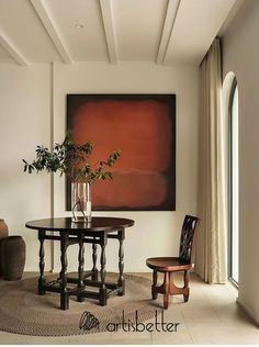 a room with a table, chair and vase on the floor next to a large painting