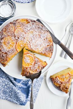 a cake with powdered sugar on top is sitting on a plate next to two plates