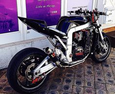 a black and white motorcycle parked in front of a purple sign on the side of a building