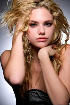 a woman with long blonde hair posing for the camera