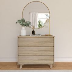 a dresser with a mirror and plants on it in front of a white wall that has a wooden floor