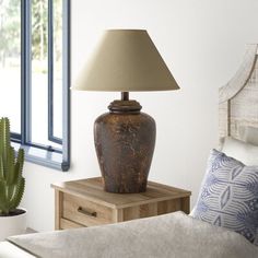 a bedroom with a bed and a lamp on the nightstand in front of the window