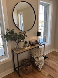 a living room with a mirror, plant and two baskets on the floor in front of it