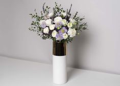 a white vase with purple and white flowers in it