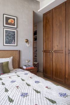 a bedroom with a large bed and wooden closets in the corner, along with pictures on the wall