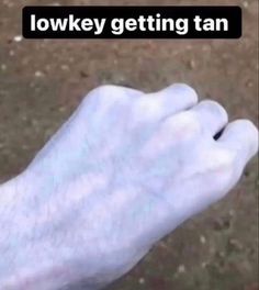 a white hand holding something in it's palm with the words low key getting tan