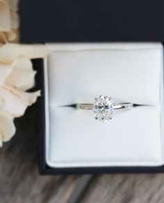 an engagement ring sitting in a box next to flowers