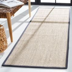 a large rug is on the floor in front of a chair and table with an open window