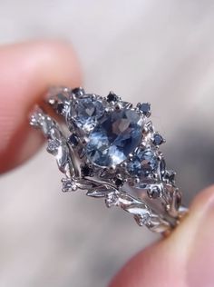 a close up of a person's hand holding a ring with blue and white stones