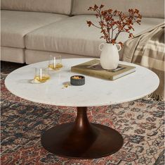 a living room with a couch, coffee table and vase on the floor in front of it