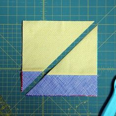 a pair of scissors sitting on top of a cutting board next to a piece of fabric