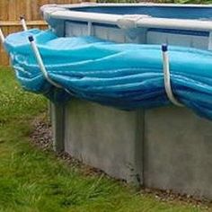 an above ground swimming pool with blue tarp on the sides and green grass around it