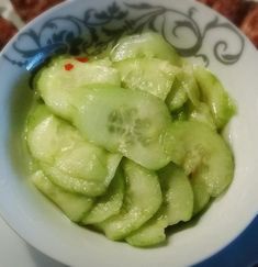 a white bowl filled with cucumber slices on top of a blue and white plate