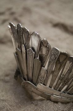 a pile of silver spoons sitting on top of a table next to a quote