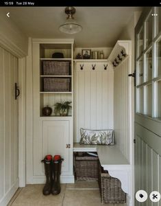 the inside of a mud room with white walls and wooden shelves, two baskets on each shelf