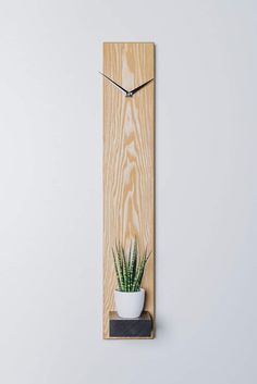 a wooden wall clock with a plant on the front and back of it, mounted to a wall