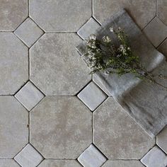 a towel and some flowers on a tile floor in a room that looks like hexagonal tiles