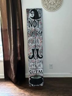 a tall wooden sign sitting on top of a hard wood floor next to a window