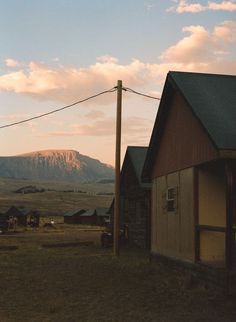 an old barn sits in the foreground with a mountain in the backgroud