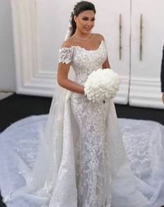 a woman in a white wedding dress holding a bouquet and standing next to another man